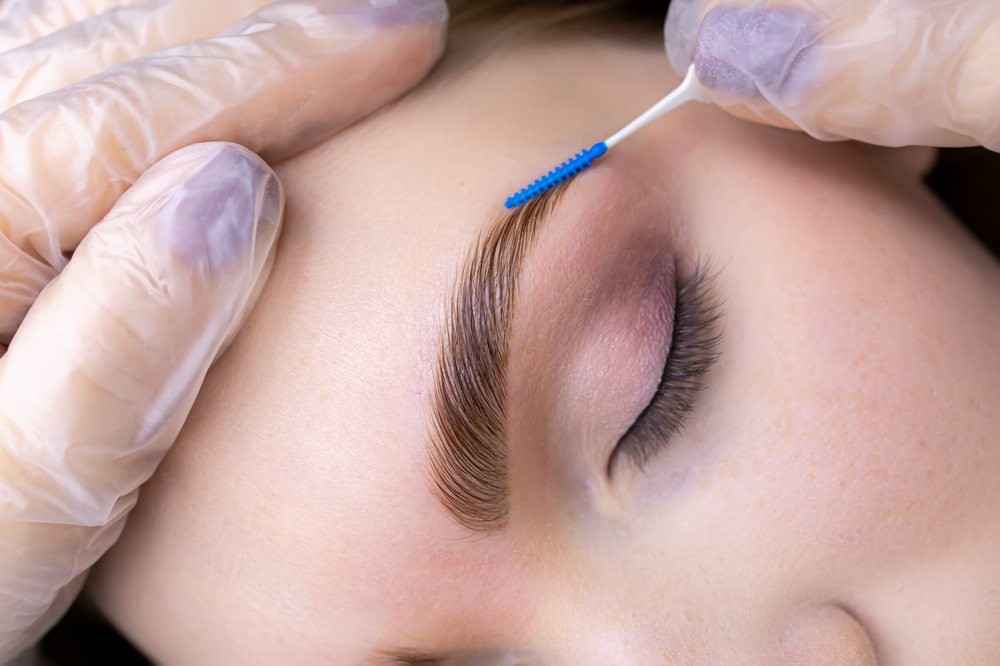 combing the hairs after laminating the eyebrows with a blue brush