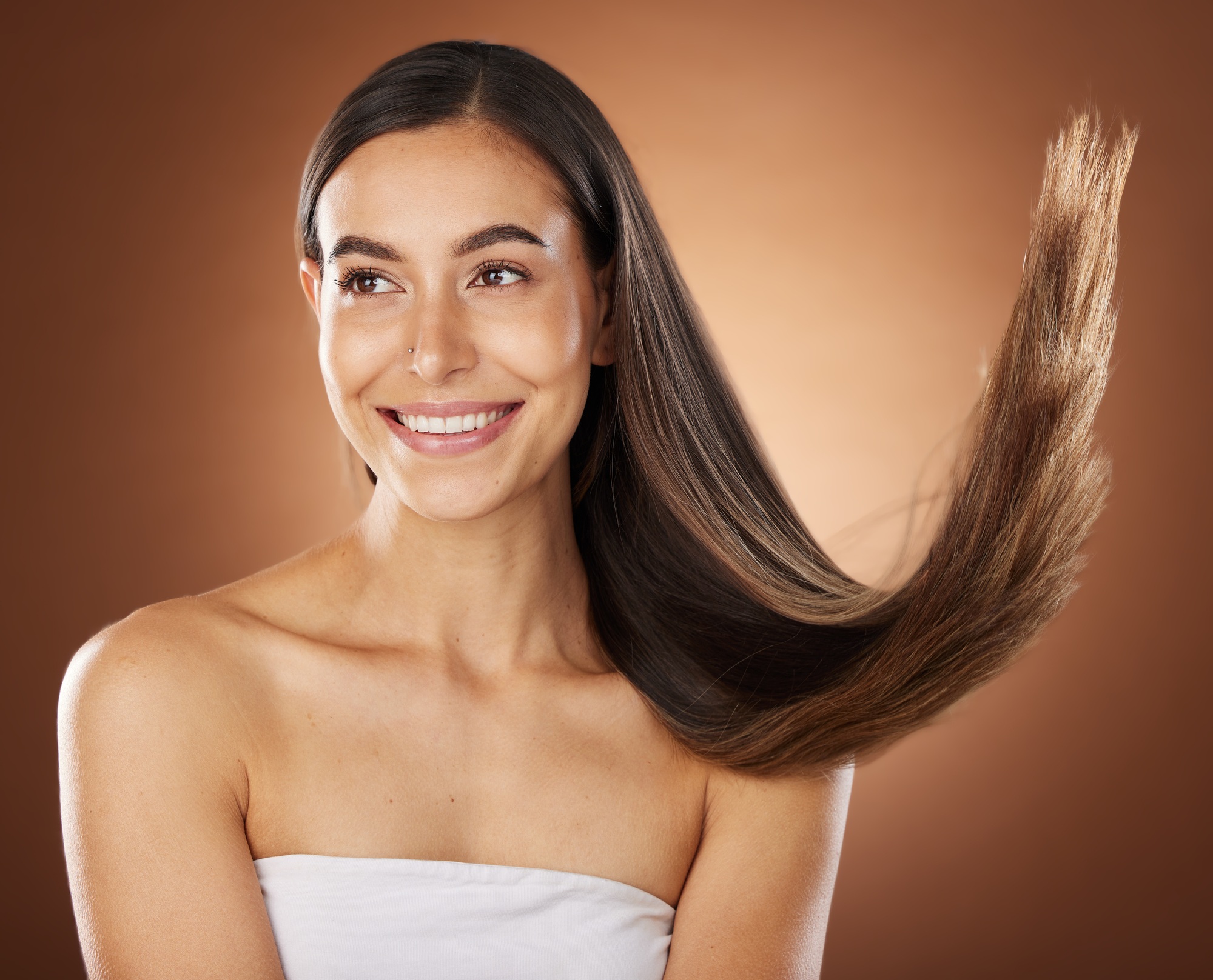 Hair, beauty and skincare with a model woman in studio on a brown background for natural or keratin