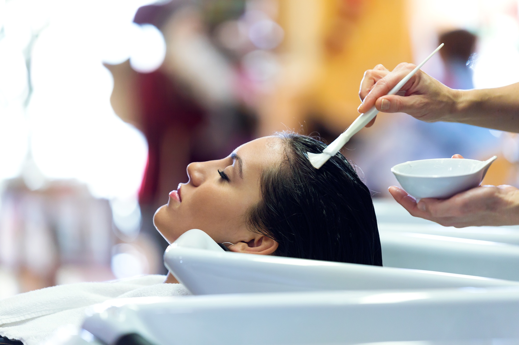 The hairdresser applying hair treatment for customer in a beauty