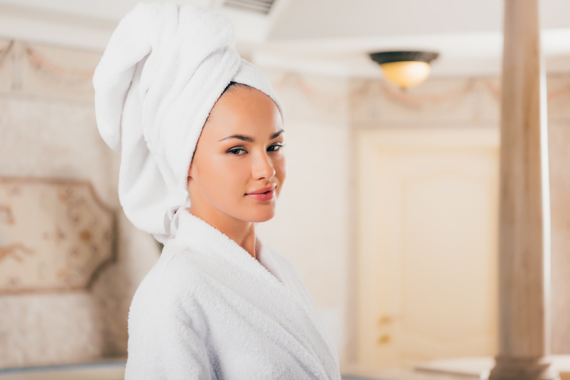 young woman in bathrobe with towel on head at spa salon